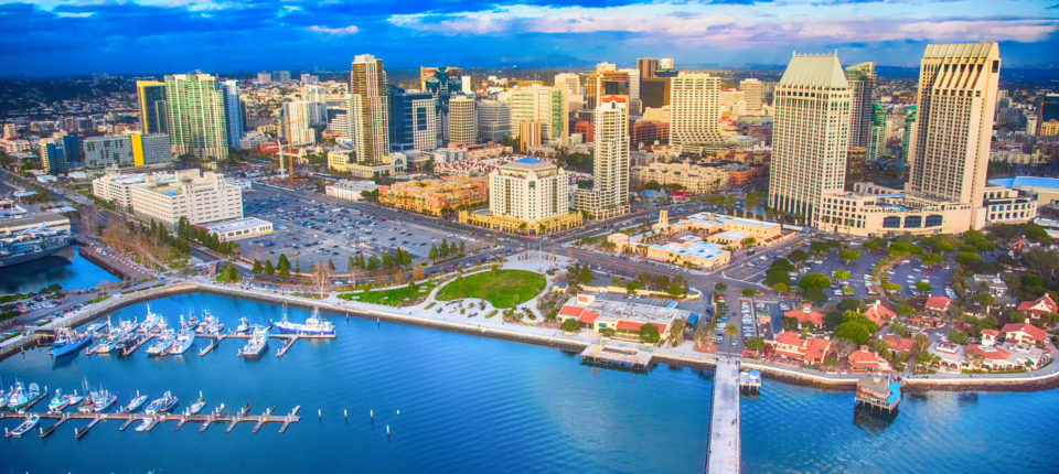Aerial view of San Diego city with vehicles, boats, and the San Diego skyline in the distance