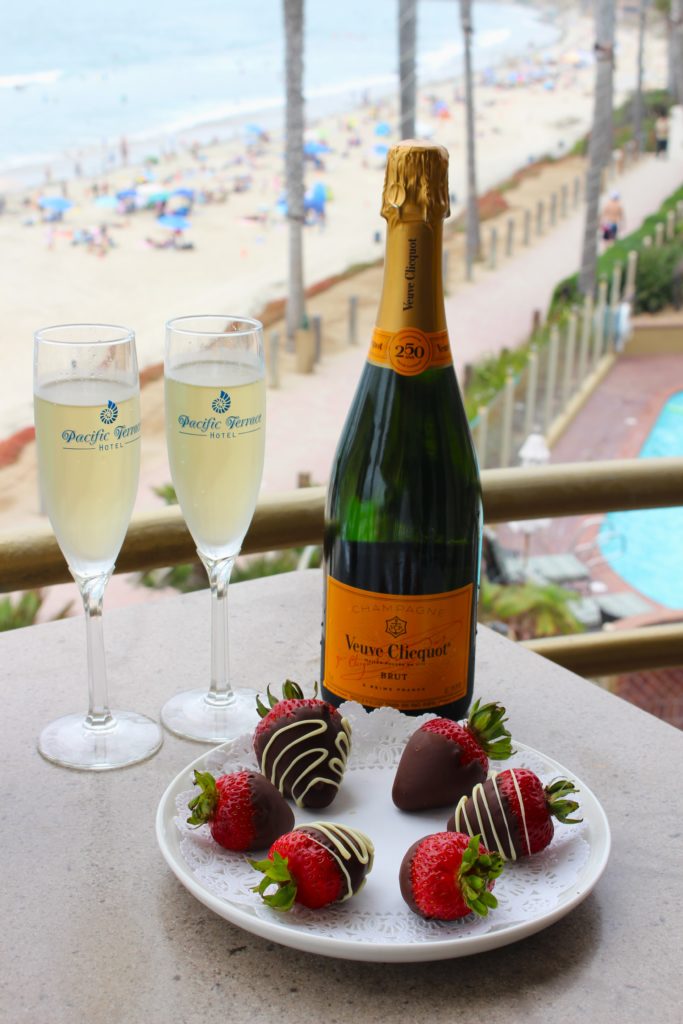 chocolate covered strawberries and bottle of champagne overlooking pool and beach