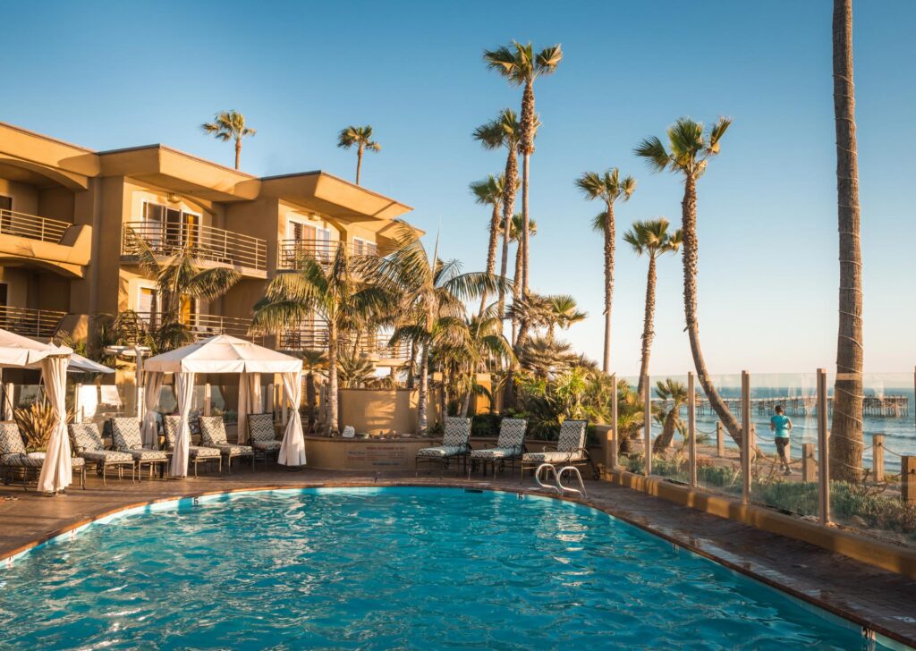 A beautiful hotel pool area with inviting lounge chairs and tall palm trees, creating a perfect spot for relaxation.