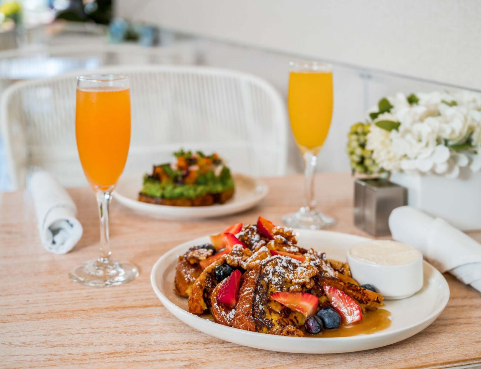 Two glasses of juice, fresh toast, and avocado toast