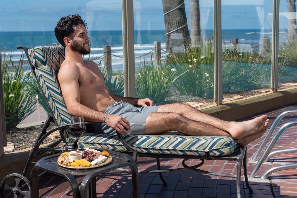 Man smiling while sitting on a poolside bench.