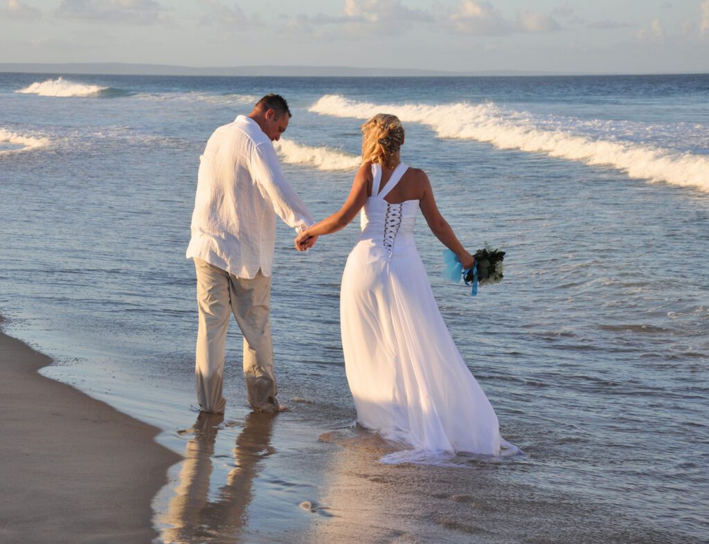 bride and groom walking in the surf