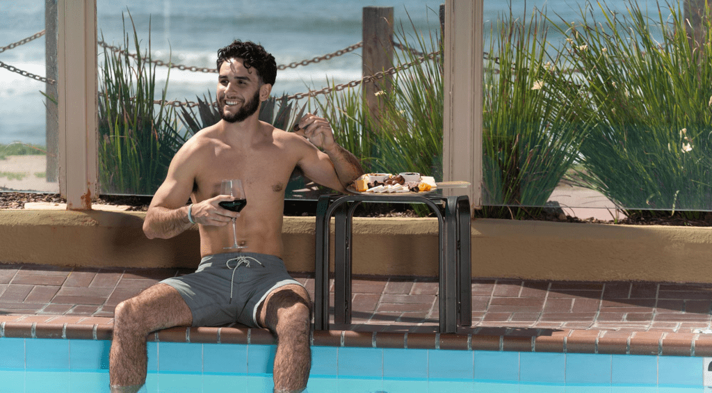 man drinking wine by the pool