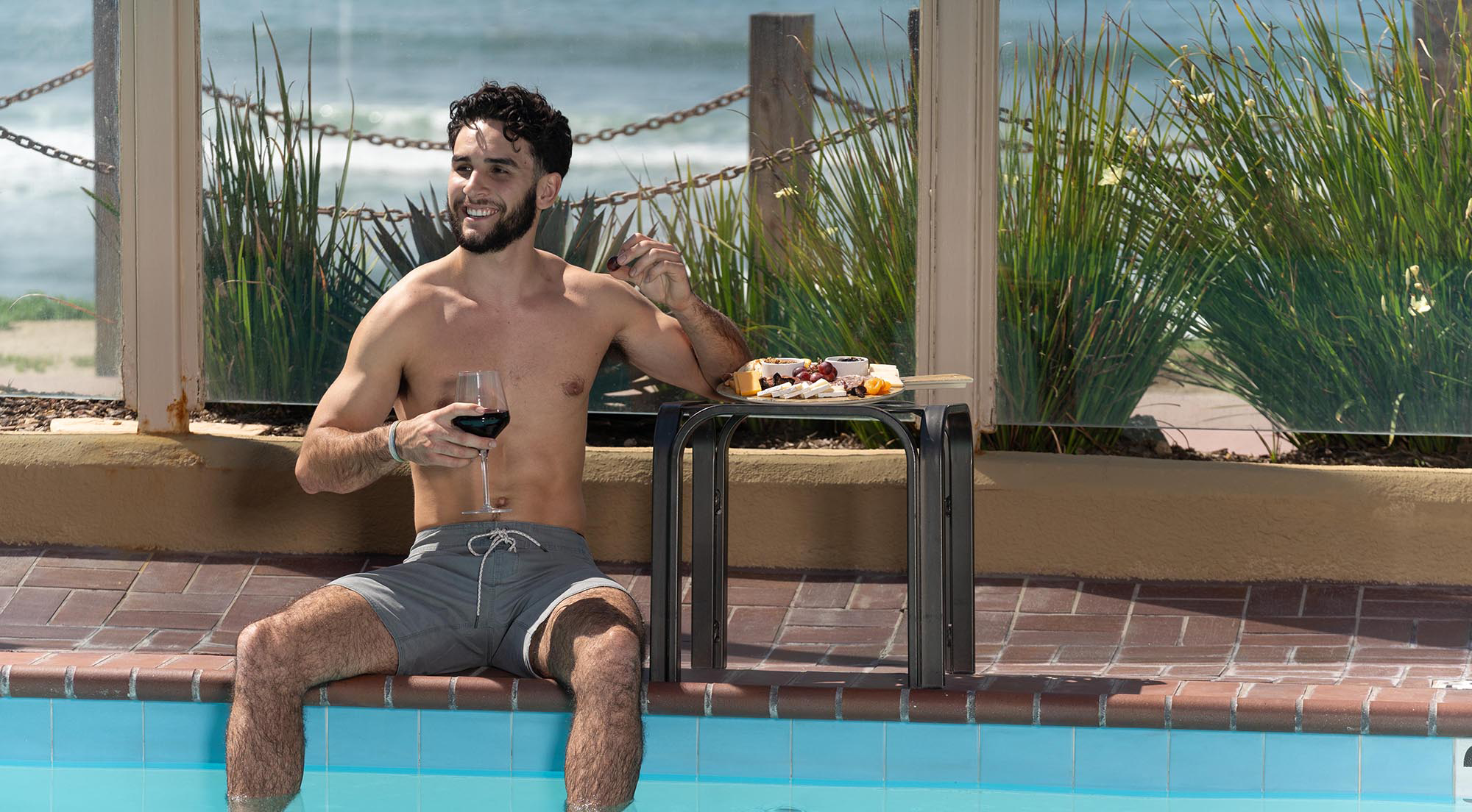 man drinking wine by the pool