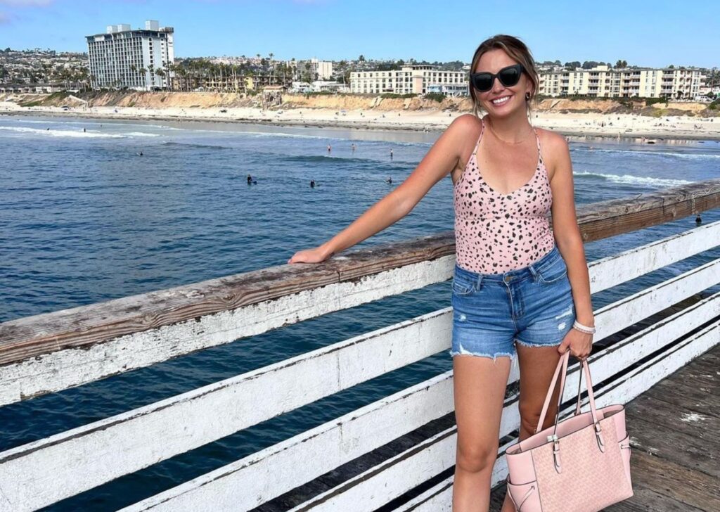 a woman posing with her bag on a pier
