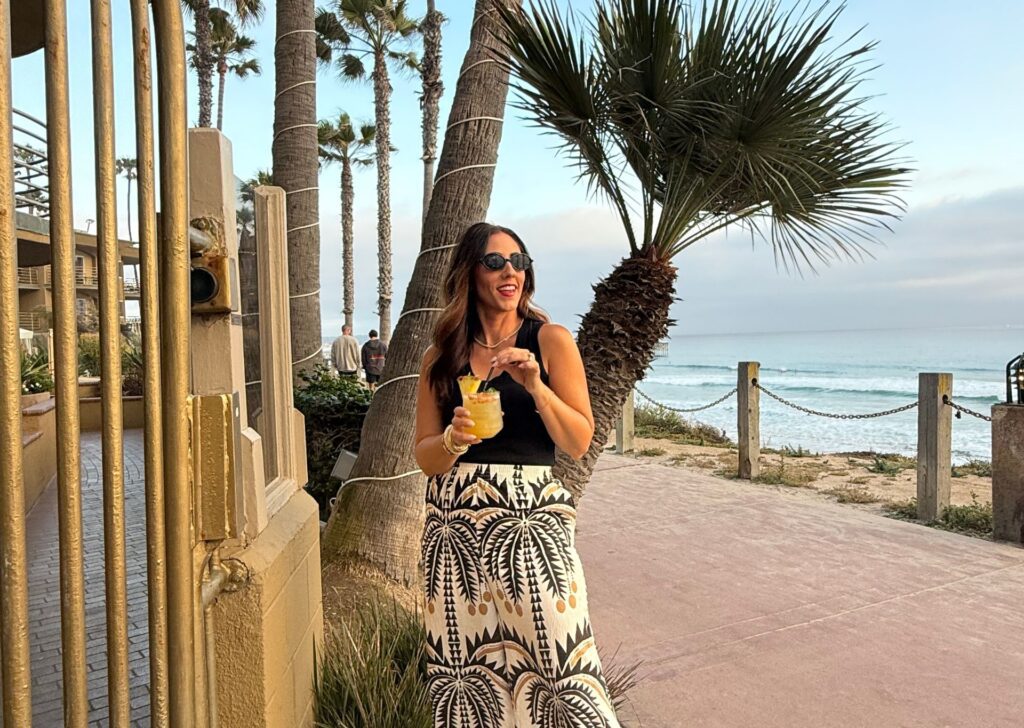 a woman posing with a drink by the beach