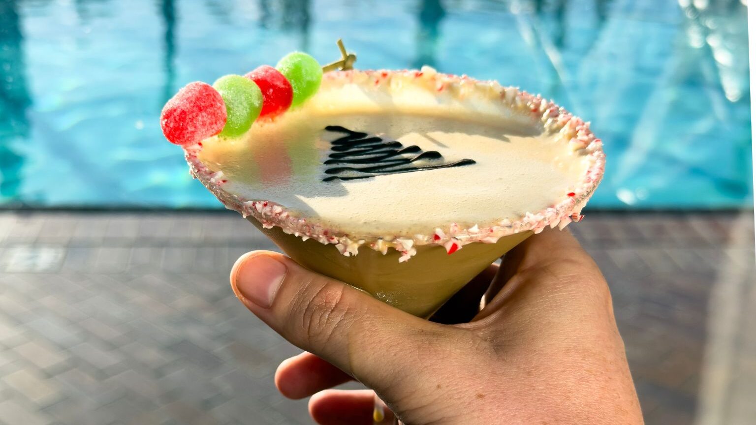 someone holding drink in front of pool