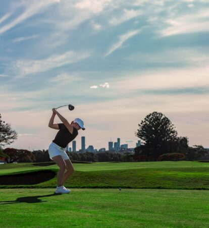 a golfer swings in front of the skyline