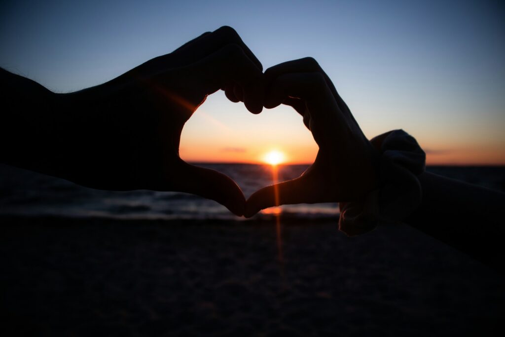 hands making a heart in front of the sunset